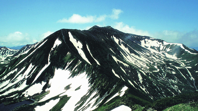 山肌に生えて植物に黒く影がかかり、いたる所に雪が積もっている幌尻岳を山の中腹から撮影した写真（幌尻岳のページへリンク）